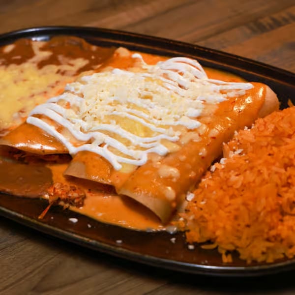 Three enchiladas covered in red sauce, cheese, and sour cream, served with rice and refried beans.