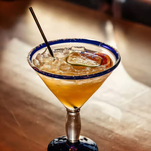 Santo Tequila margarita with a salted rim, lime, and straw, on a wooden table.